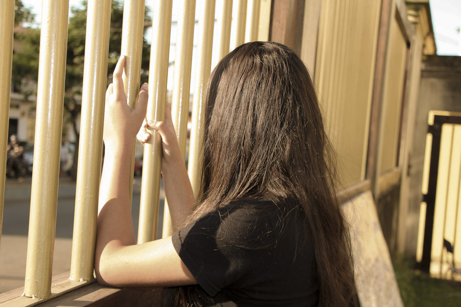 Menina de costas apoiada em grade