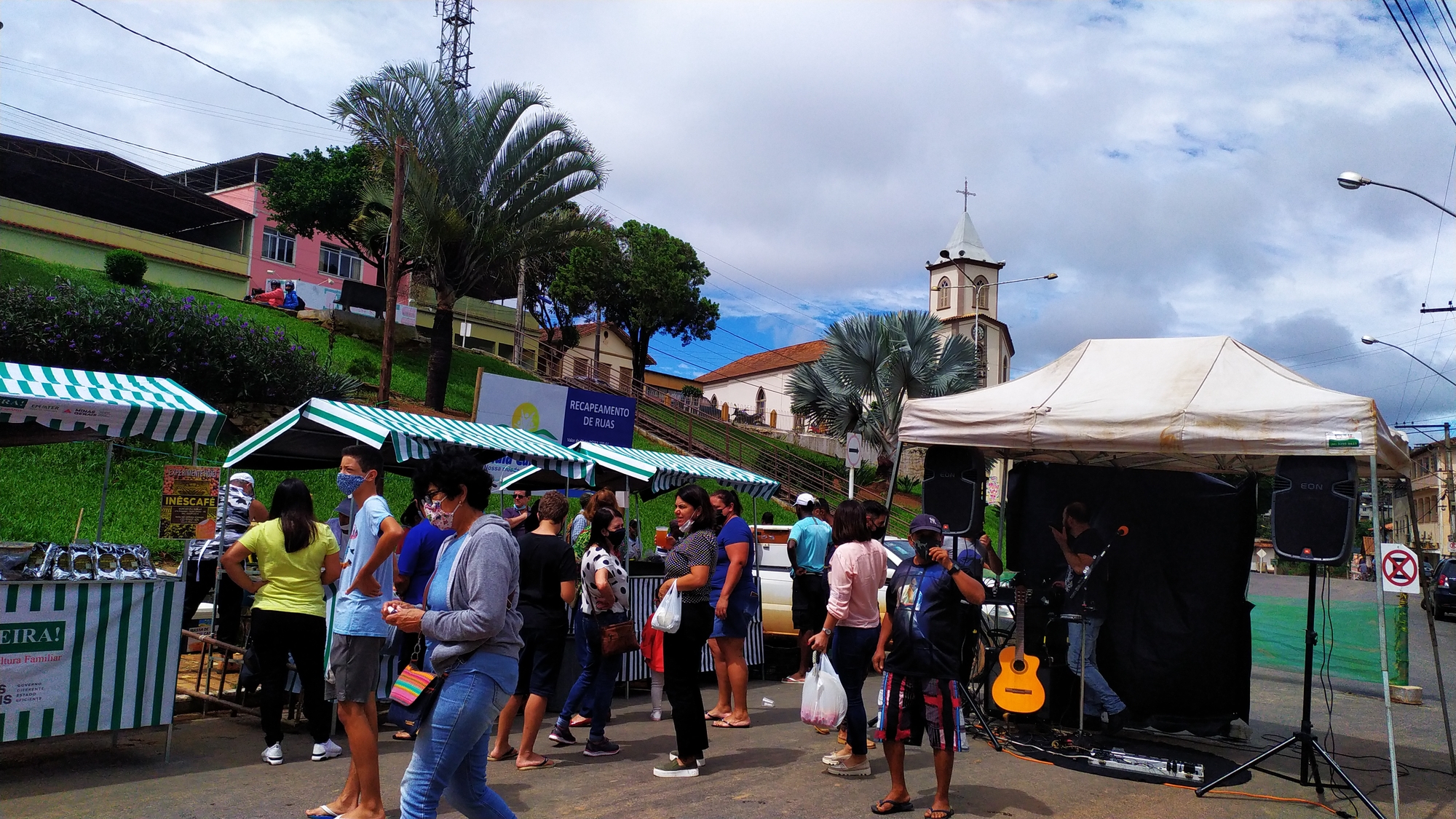 Foto tirada no centro da cidade de Paula Cândido, aparece as barracas dos feirantes, artista musical e os visitantes)