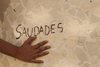 Mão de menino sobre a palavra saudade